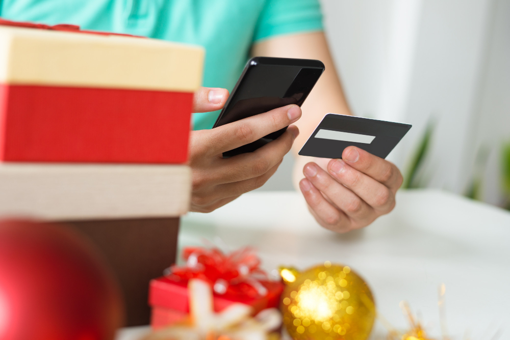 Gros plan de l'homme avec carte de crédit, smartphone et cadeaux de Noël