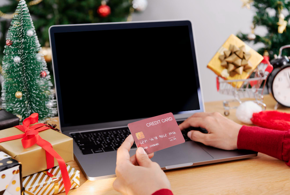 Happy Woman Holding Credit Card faisant des achats en ligne présents à Noël